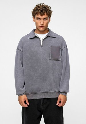 Grijze pullover sweatshirt met een ritssluiting aan de kraag, een voorzak en geribde manchetten. Zachte textuur, losse pasvorm en casual ontwerp.