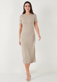 Beige short-sleeve dress made from smooth, stretchy fabric, featuring a midi length and side slits for ease of movement.