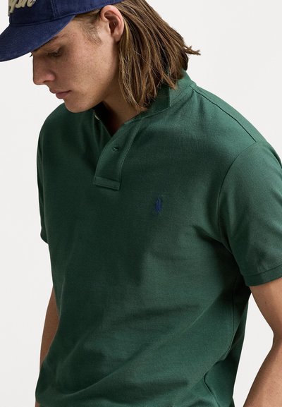 Groene katoenen polo met een gestructureerde afwerking, voorzien van een twee-knopenplacket en een klein blauw logo op de borst.