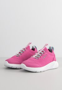 Zapatillas rosas con parte superior de punto, cordones elásticos y suela blanca. Presenta un logotipo en el lateral y acentos en azul contrastante en el talón.