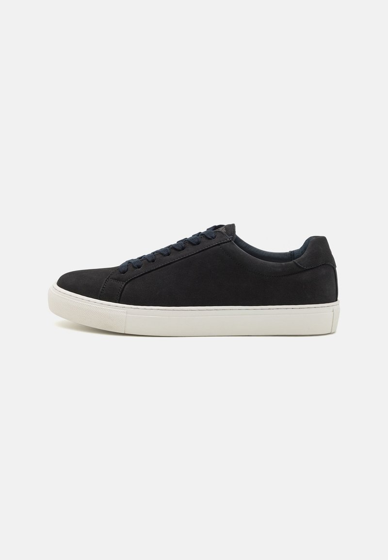 Black suede sneaker with a rounded toe, white rubber sole, contrasting blue laces, and a smooth texture. Minimalist design with no visible logo.