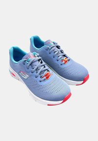 Par de zapatillas deportivas Skechers Arch Fit de color azul claro con suelas blancas y acentos rojos, mostradas sobre un fondo blanco.