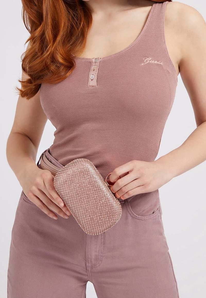 Prachově růžový žebrovaný top bez rukávů se třemi knoflíky a malým logem, kombinovaný s lesklou růžovou diamantovou kabelkou.