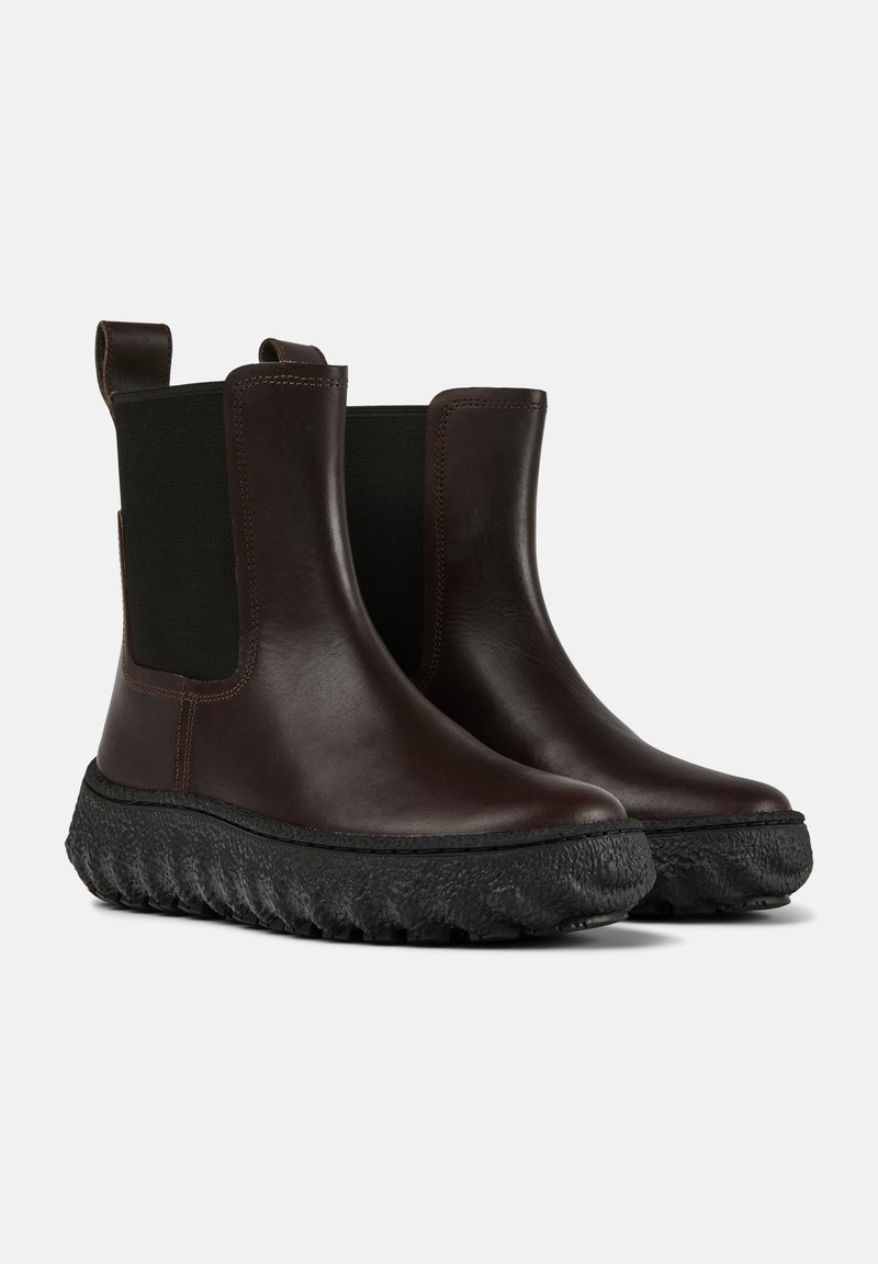 Bruine leren enkellaarzen met elastische zijpanelen, gestructureerde zwarte rubberen zolen en een trekriem aan de achterkant. Chunky en afgerond ontwerp.