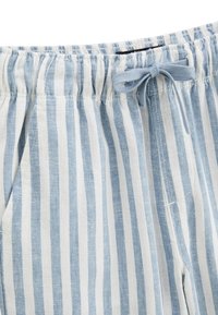 Tissu léger à rayures bleues et blanches avec une taille élastique et un lien contrastant. Dispose de poches latérales et d'une texture douce.