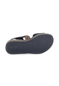 Zwarte slip-on sandaal met een gestructureerde rubberen zool, voorzien van twee banden en een lichtgekleurde binnenvoering. Merken zichtbaar op de zool.