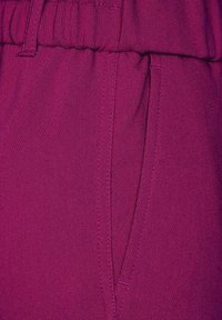 Fuchsia tyg med en slät textur, med en elastisk midja, sidoficka och snygga sömmar.