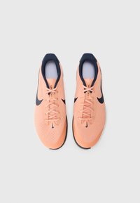 Nike tenisice za trčanje s laganom, prozračnom gornjom dijelom od breskve mrežice, mornarskim akcentima, fleksibilnim gumeni potplatom i ravnim vezicama.