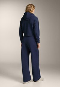 Námornícky modrá skrátená mikina s rebrovanou textúrou a širokými zodpovedajúcimi nohavicami, s uvoľneným strihom a minimálnymi detailmi. Mäkká látka.