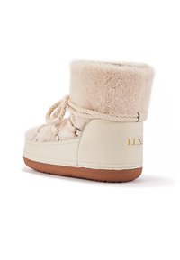 Biely šedý kotník s ovčou vlnou a pletenou šnúrkou, krémovými koženými akcentami, textúrovanou gumovou podrážkou a embosovaným zlatým logom na päte.