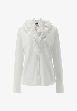 Weißes Langarmhemd mit strukturiertem Rüschensaum, durchgängiger Knopfleiste und glattem Stoff. Das schlichte Design legt den Fokus auf Schichtung und Eleganz.