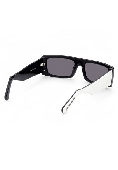 Occhiali da sole in plastica nera con lenti scure e un'unica accentatura bianca sui bracci laterali. Design angolare e slanciato con una finitura lucida.