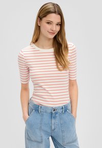 Witte ribgebreide T-shirt met koraalkleurige horizontale strepen, ronde halslijn en korte mouwen, gecombineerd met lichtblauwe denim broek met zakken.