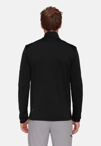 Schwarzer, langärmeliger Pullover mit hohem Kragen. Glattes, texturiertes Material mit Akzenten an den Schultern und seitlichen Panels. Minimalistisches Design, Rückansicht.