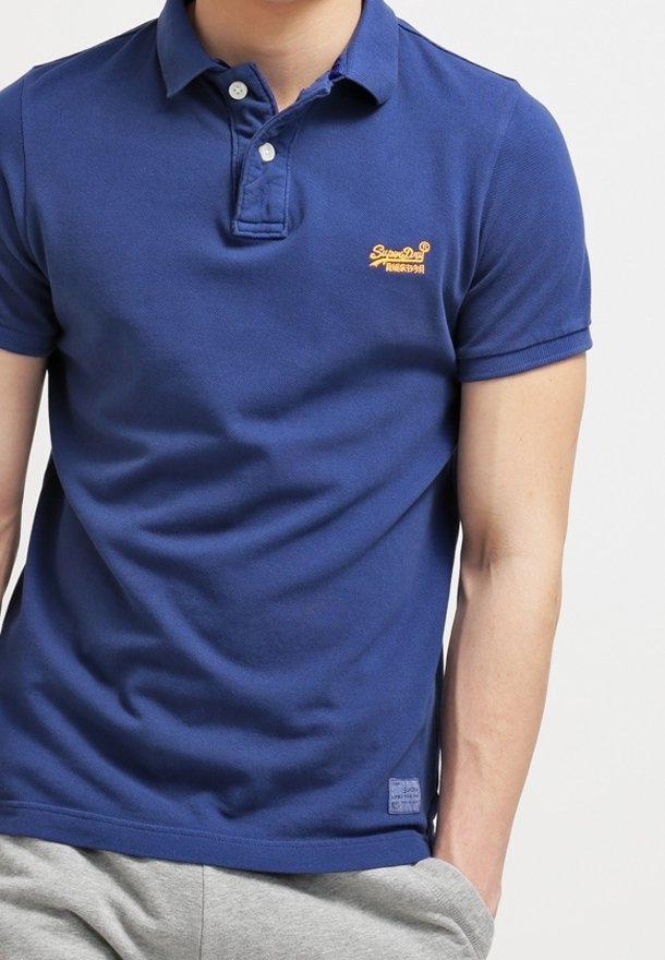 Mörkblå pikétröja i bomull, med en treknapprad, korta ärmar och en broderad logotyp på bröstet.