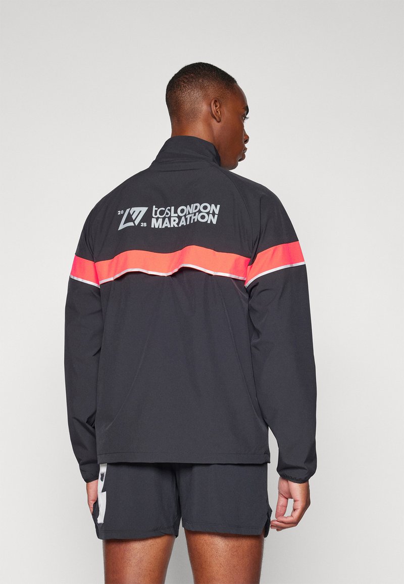 Black athletic jacket with a high collar, featuring a pink horizontal stripe and reflective accents. Back displays "tcs LONDON MARATHON 2025" text.