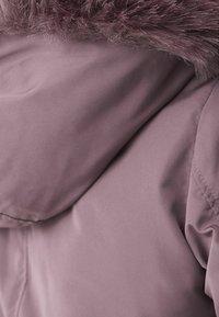 Veste mauve clair avec une texture lisse, dotée d'une capuche en fausse fourrure et d'accents cousus sur les épaules et le col.