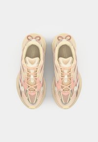 Tenisky Lacoste v krémovo-růžovo-béžovém provedení s panelováním z prodyšné síťoviny, texturovanými detaily a výraznými tkaničkami s očky.