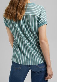 Turkisstribet t-shirt med afslappet pasform, korte ærmer og rund halsudskæring, lavet af tekstureret stof, parret med mørkeblå jeans.