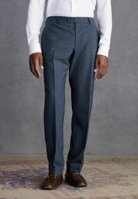Maßgeschneiderte Anzughose aus dunkelblauem Stoff mit subtilen Mustern, ausgestattet mit einer flachen Vorderseite, Seitentaschen und einem schlanken Schnitt.