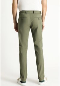Pantalones verde oliva de corte slim, fabricados en tejido suave, que cuentan con dos bolsillos traseros con botones y detalles de costura sutiles.