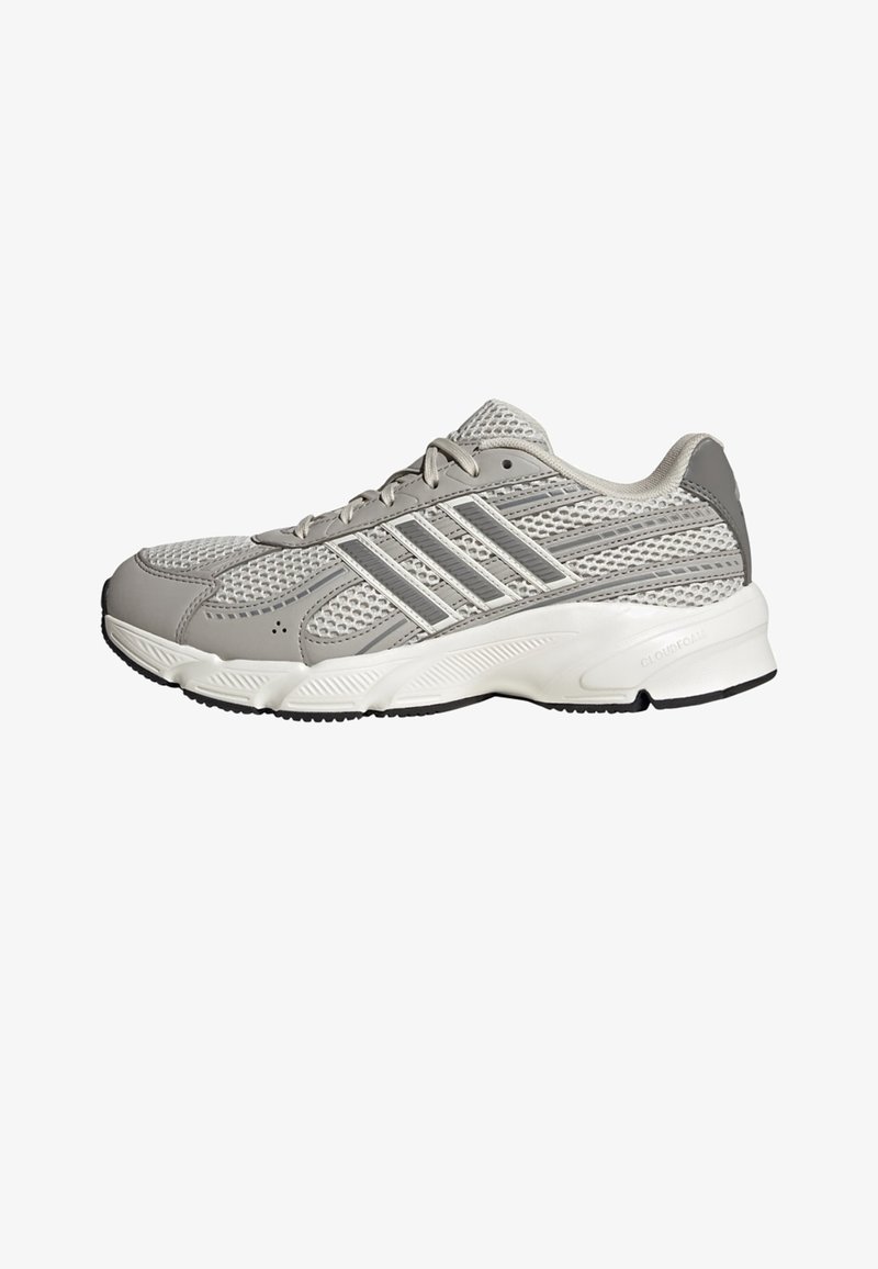 Baskets athlétiques grises et blanches avec dessus en mesh, fermeture à lacets, et semelle amortissante, vues de profil sur un fond blanc.