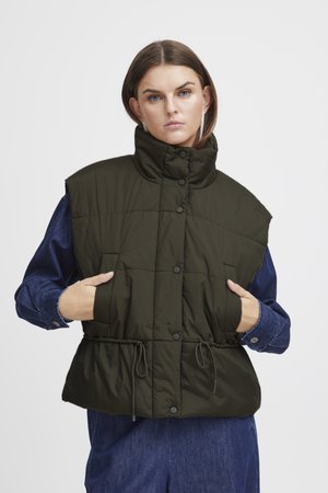 Knie-lange, olijfgroene gewatteerde vest met hoge kraag. Bevat drukknopen, zijzakken en een cinch taille met trekkoord. Draagt over een denim shirt.
