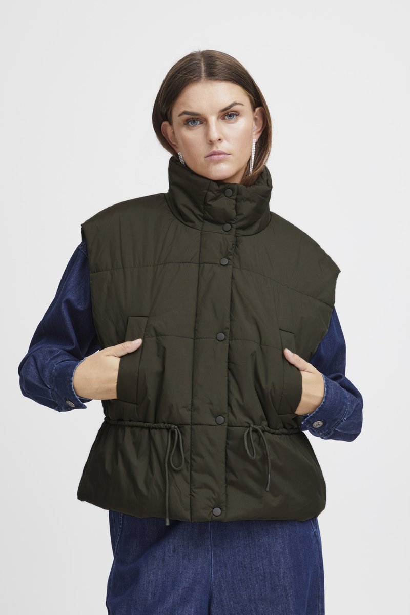 Knee-pikkune, oliivrohelise värvi paks vest kõrge kraega. Omab nööpklappe, küljetaskuid ja tõmbluku sees oleva vöökohtade reguleerimist. Kantud teksasärgi üle.