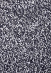 Dzianina w ciemnoszarym kolorze z jasnoszarymi drobinkami, charakteryzująca się fakturowanym wzorem splecionych nici, oferująca miękki, przytulny wygląd.