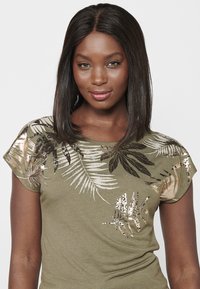 T-shirt vert olive à manches courtes avec des motifs de feuilles en feuille métallique dorée et bronze. Tissu doux et texturé avec une coupe cintrée.