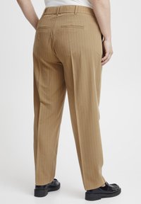 Bruin gestreepte broek met een rechte snit, voorzien van een middelhoge tailleband en platte achterzakken. Draag met zwarte instappers.