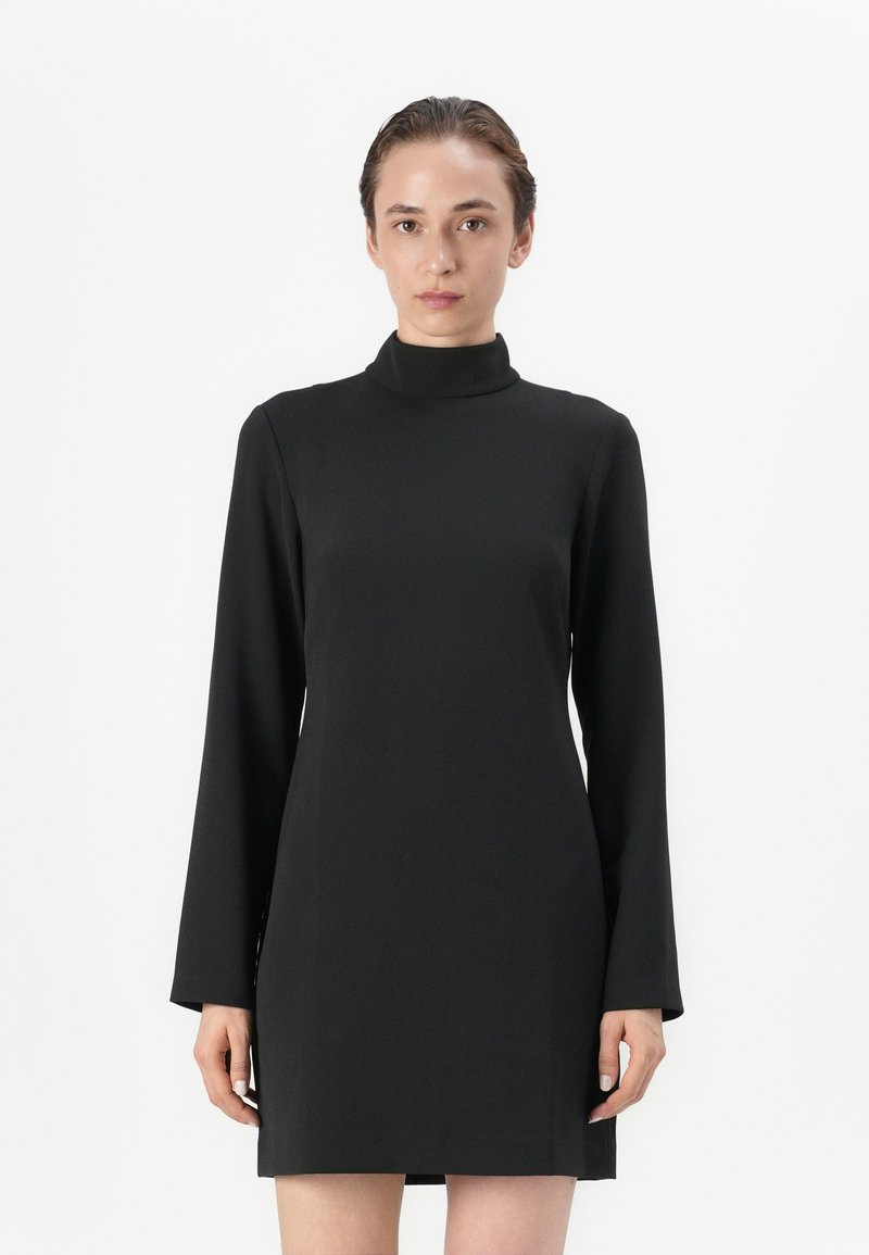 Robe noire à col montant en tissu lisse, dotée de manches longues et d'une coupe évasée, avec une longueur au-dessus du genou et un design minimaliste.