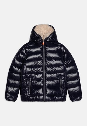 Doudoune noire brillante avec capuche doublée en polaire beige, fermeture éclair devant et deux poches zippées, posée à plat sur fond blanc.
