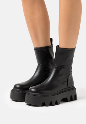 Czarne skórzane botki za kostkę z grubą platformą. Posiadają gładką fakturę i elastyczne boczne panele dla łatwego zakupu.