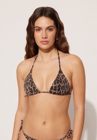 Top de bikini triangular con estampado de leopardo, tirantes finos y detalles de lazo ajustables, que presenta una textura suave y colores marrones y negros en tonos tierra.