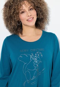 Türkises Langarmshirt mit Rundhalsausschnitt, das eine silberne Linienzeichnung eines Kaninchens und den Text "FROHE WEIHNACHTEN" zeigt. Glatte Stofftextur.