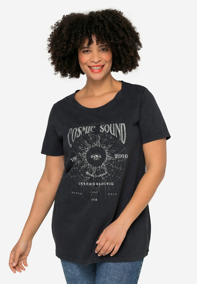 Camiseta de algodón negra con un corte relajado, que presenta un diseño gráfico con el texto "Sonido Cósmico" y un motivo de ojo en blanco, de manga corta.