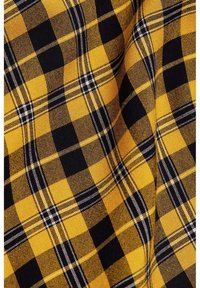 Tessuto a quadri giallo e nero con una trama strutturata, caratterizzato da grandi quadrati con sottili linee bianche e una predominanza di colori solidi.