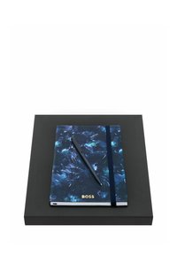 Carnet marbré bleu marine avec l'inscription « BOSS », élastique noir et stylo noir, posé sur une boîte rectangulaire noire.