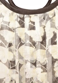Przezroczysta bluzka z kwiatowym nadrukiem w beżu i bieli, z pionowymi paskami, okrągłym dekoltem i kontrastowym ciemnym wykończeniem.