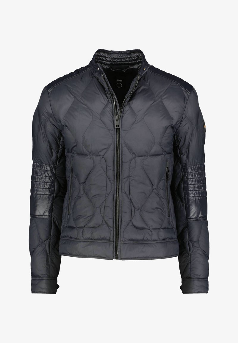 Tummansininen tikattu takki, jossa on korkea kaulus, olkainkorostukset, vetskarsikiinnitys ja kaksi etutaskua, joissa on ribbikirjailut hihoissa.