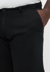 Sorte bomullsbukser med en glatt tekstur, med sidelommer og en linning med knapplukking. Slim-fit design.