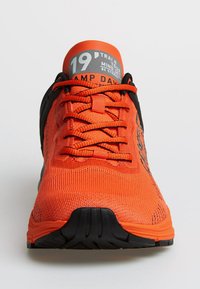 Orange Sport Schuhe mit einem Obermaterial aus Netzgewebe, schwarzen Akzenten und leuchtenden Schnürsenkeln. Verfügt über einen gepolsterten Schaft und eine strukturierte schwarze Laufsohle.