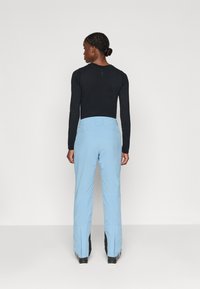 Helle blaue Skihose mit geradem Beinschnitt, ausgestattet mit einem hohen Bund und schwarzen Akzenten am Saum. Hergestellt aus glattem, strapazierfähigem Material.