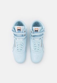 Ljusblå högstövlar i läder med slät yta, perforerat tåsyd och vita detaljer. Har platta snören och märkta tunglappar.