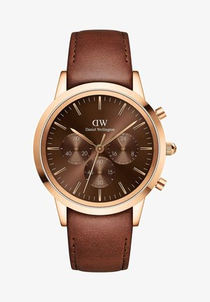 Bruin lederen strap horloge met een ronde roségouden kast, donkerbruine wijzerplaat, chronograaf subdials en zilveren uurmarkeringen. Merk: Daniel Wellington.