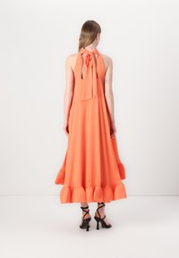 Μάξι φόρεμα σε φωτεινό πορτοκαλί ύφασμα με σχέδιο λαιμόκοψης και ζωνάκι, που διαθέτει φουσκωτό στρίφωμα με ριγέ άκρες και ανοιχτή πλάτη.