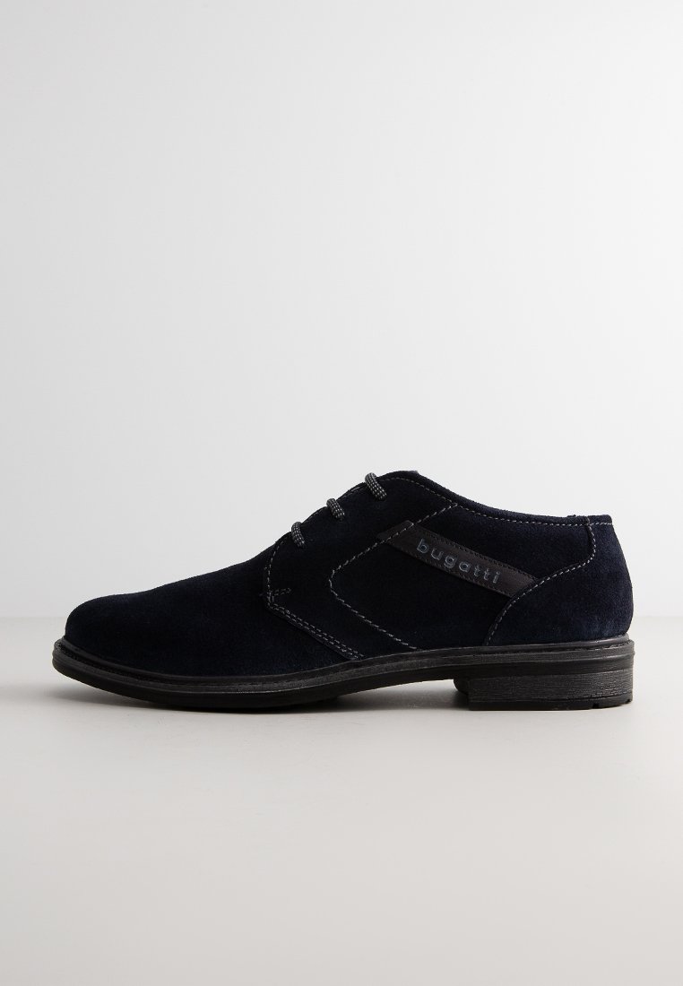 Marineblauwe suède schoenen met een gladde textuur, vetersluiting en een contrasterende zwarte leren accent met de merknaam. Rubberen zool.