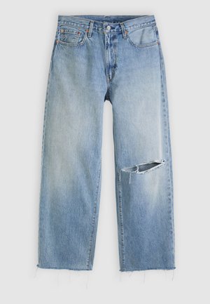 Hellblaue Jeans mit geradem Bein, großem horizontalem Riss am rechten Knie und ausgefransten Säumen, auf weißem Hintergrund.