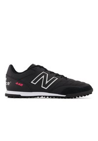 Black athletic shoe with synthetic upper, quilted texture, white and pink accents, and a rubber outsole featuring prominent studs for traction.